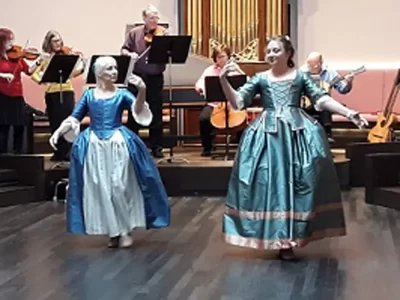 Two dancing ladies wearing blue period dresses